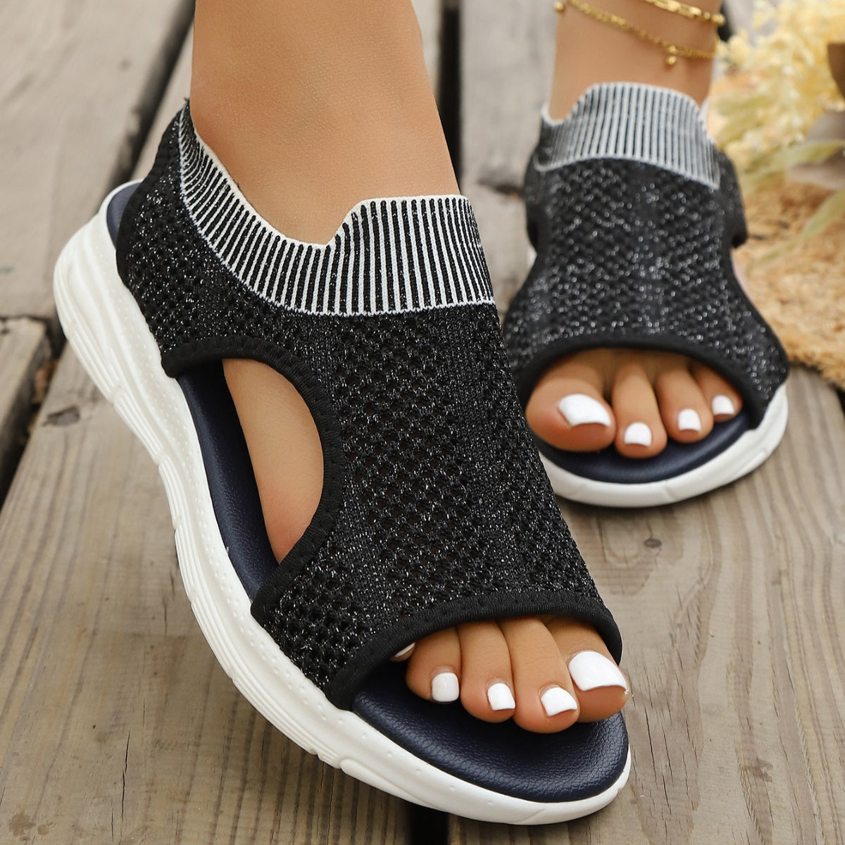 Black open-toe sandals with white striped ankle cuff and breathable knit upper.