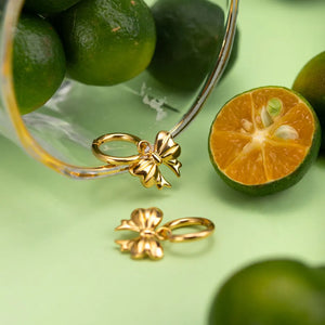 Gold hoop earrings with bow charms, 18K gold-plated.