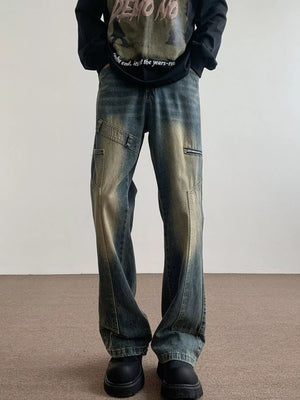Men's blue vintage wash flare jeans with distressed details and zip pockets.