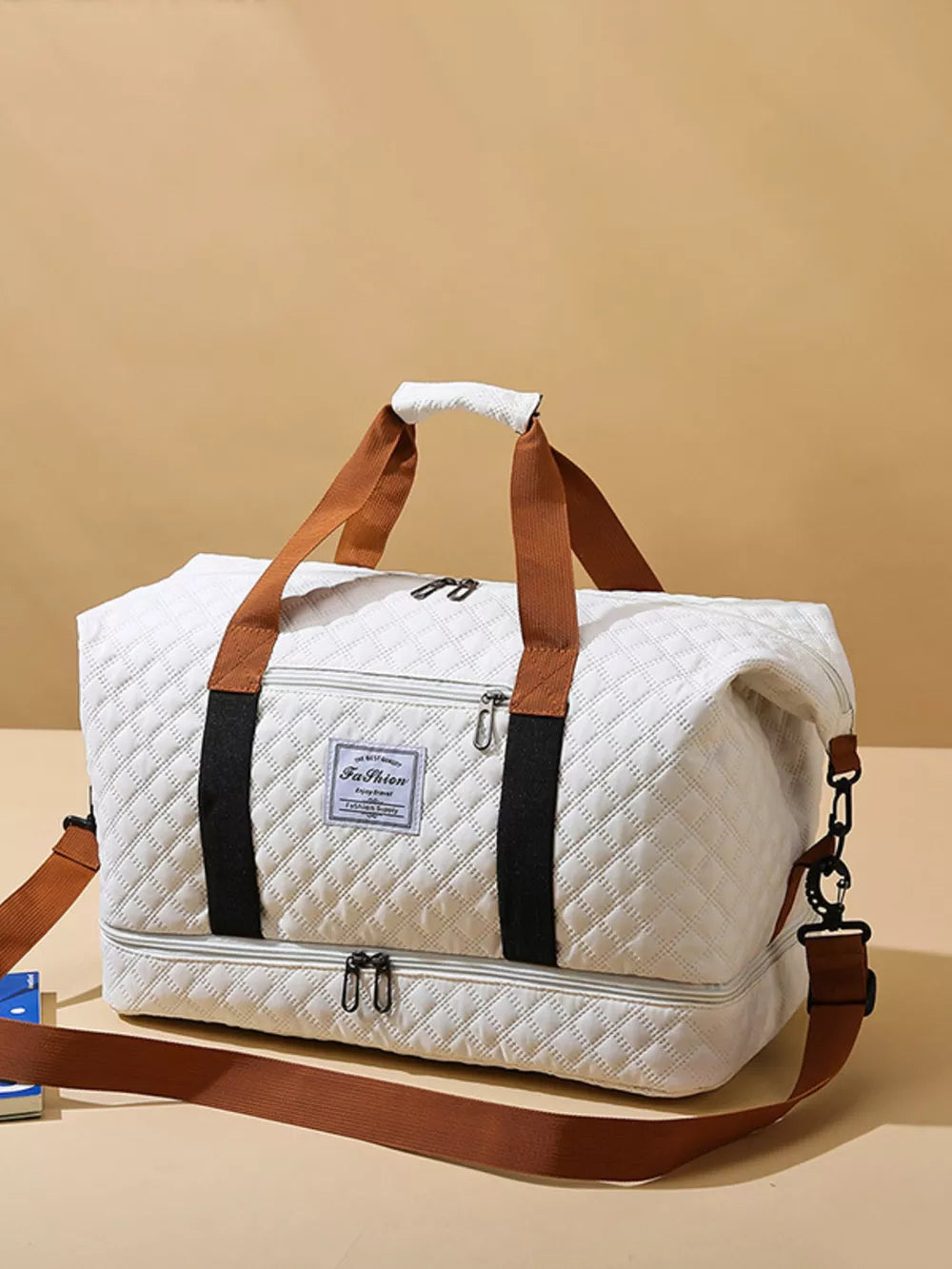 Creamy-white quilted duffel bag with brown straps and a detachable shoulder strap.