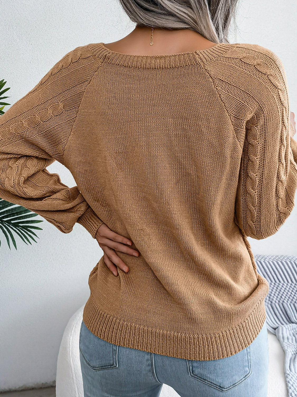 Khaki cable-knit sweater with buttoned shoulder detail and raglan sleeves.