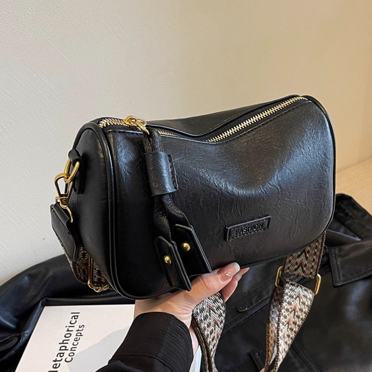 Black textured pu leather crossbody bag with a patterned strap and tassel detail.