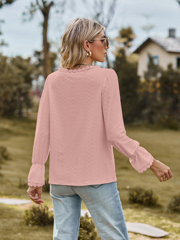 Blush pink textured blouse with lace trim neckline and bell sleeves.