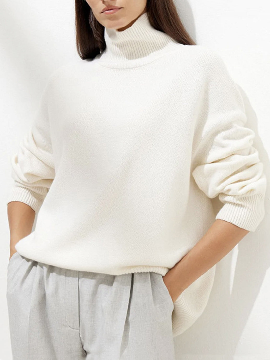 Ivory relaxed turtleneck sweater with sculptural sleeves and ribbed cuffs.