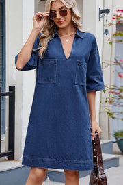 Collared denim mini dress in dark blue with two chest pockets and short sleeves.