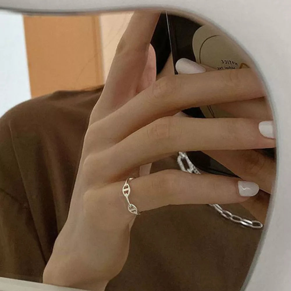 Sleek sterling silver ring with a chain-link design on a woman's finger.