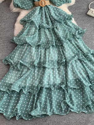 Green polka dot tiered dress with ruffle details and a woven belt.