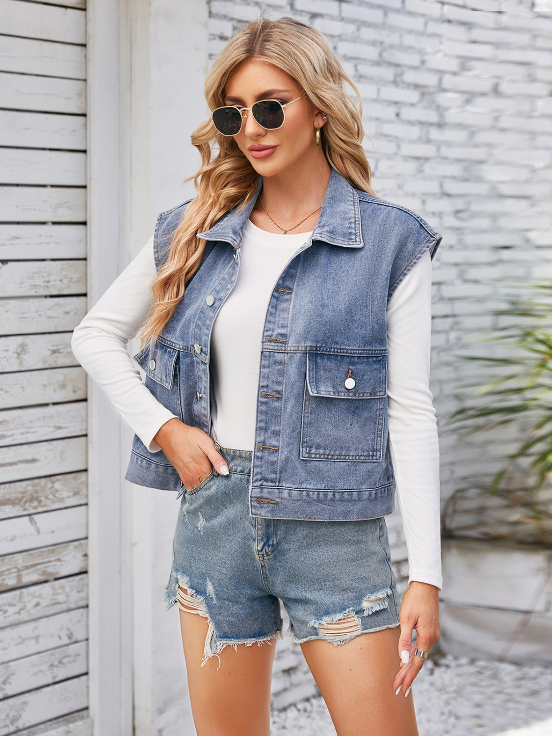 Sleeveless washed denim utility jacket in dusty blue with button front and chest pockets.