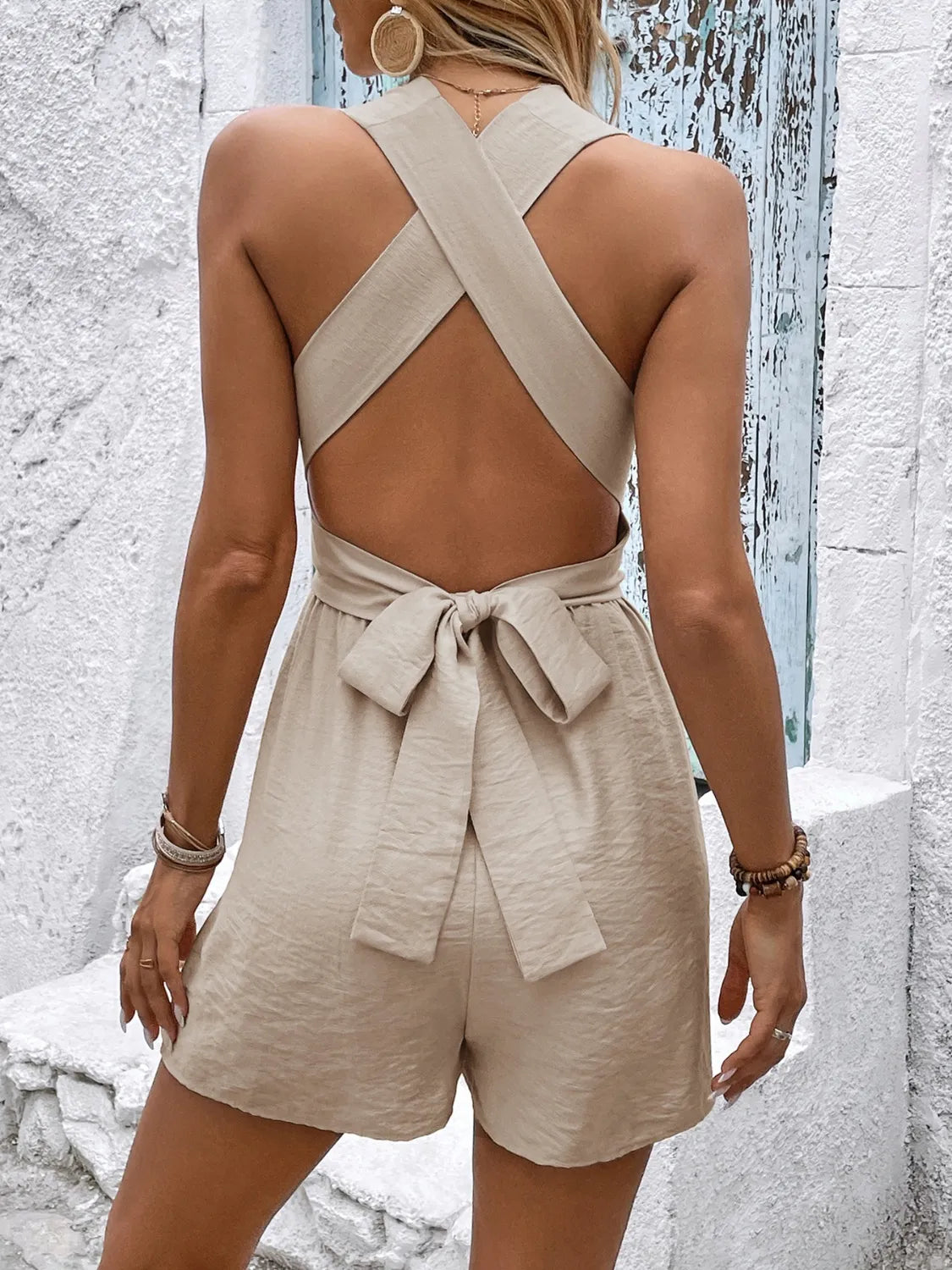 Khaki cross-back halter romper with a bow detail at the waist.