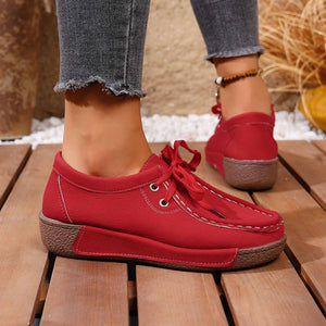 Red lace-up moccasin style sneakers with white stitching and a brown sole.