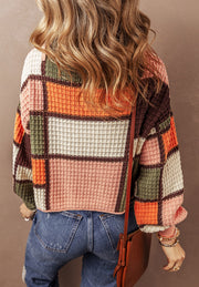 Waffle knit hoodie with patchwork colorblock design in orange, pink, green, and brown.