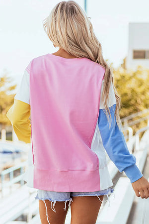 Colorblock sweatshirt in blush pink, white, yellow, and blue with a split hem and ribbed cuffs.