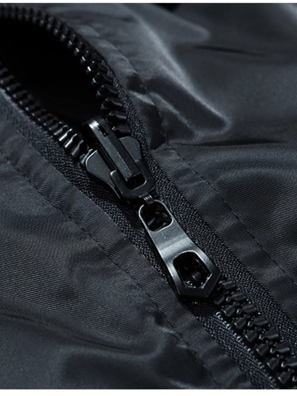 Black bomber jacket detail showing a close-up of the zipper and shiny fabric.