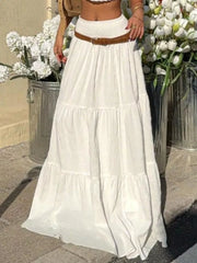 White tiered maxi skirt with smocked waist and crinkled fabric, styled with a brown belt.