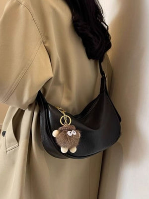 Black crescent shoulder bag with plush charm and adjustable strap