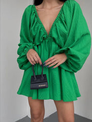 Green ruched V-neck dress with balloon sleeves and textured fabric.