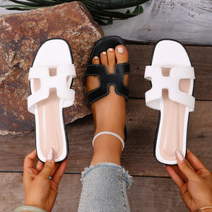 Chic H-strap open-toe sandals in black with contrast stitching and white.