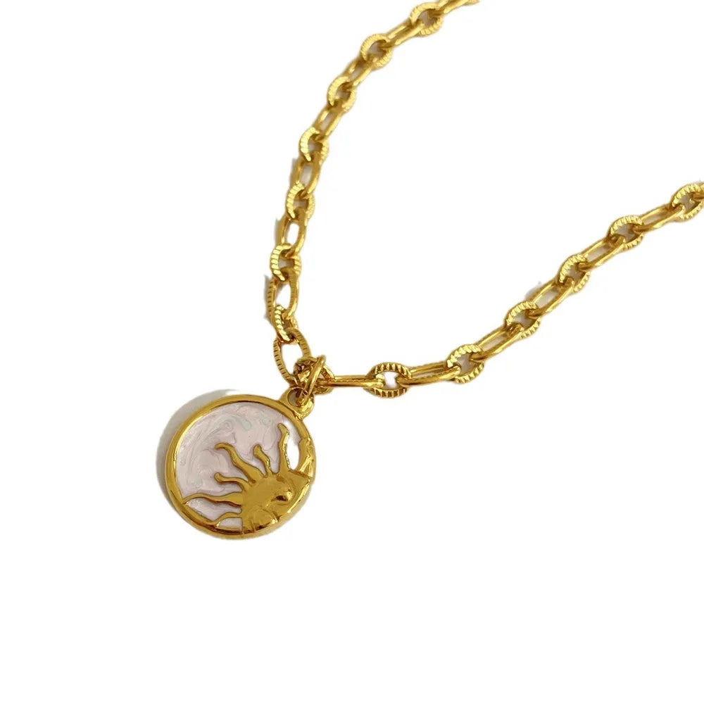 Gold chain necklace with a sunburst medallion pendant in white and gold.