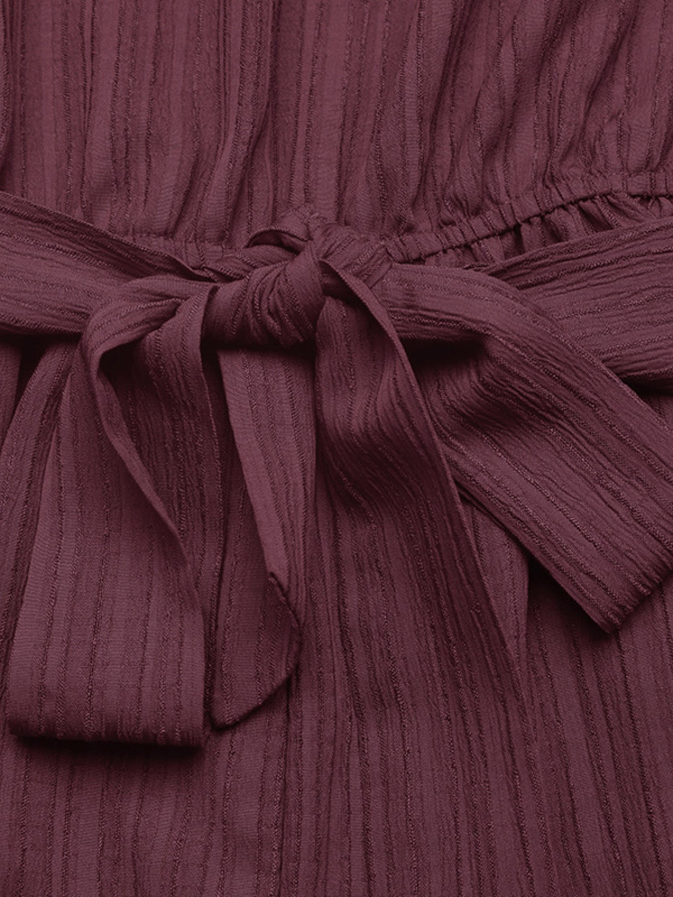 Chic one-shoulder romper in burgundy with a textured fabric and tie waist detail.