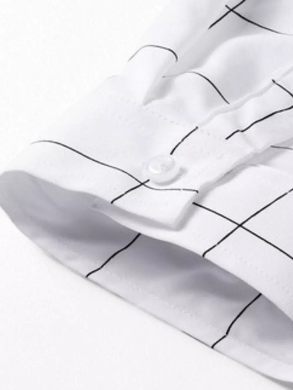 White oversized button-down shirt with black plaid print and button cuff detail.