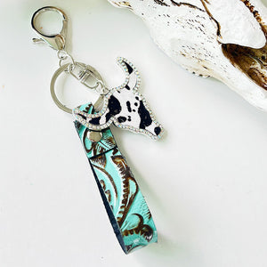 Embossed leather bull keychain with crystal accents and a cowhide print bull head charm.