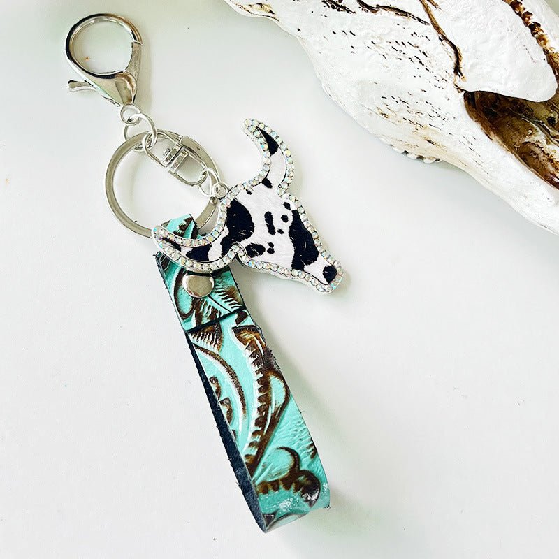 Embossed leather bull keychain with crystal accents and a cowhide print bull head charm.