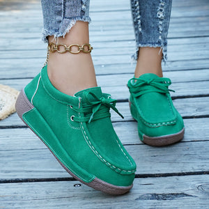 Green lace-up moccasin style sneakers with white stitching and a brown sole.