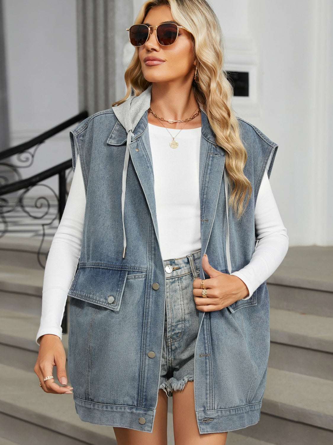 Light wash denim hooded sleeveless utility vest with chest pockets and drawstring hood