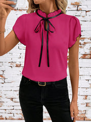 Frilled tie-neck blouse in Fuchsia Pink with black trim and bow, short flutter sleeves.