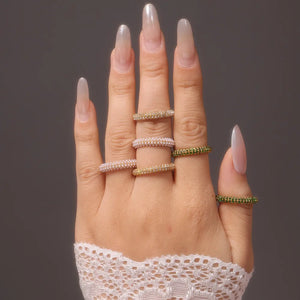 Pavé zirconia band rings in gold, white pearl, and dark green sparkle.