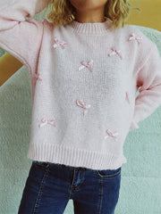 Blush pink knit crewneck sweater with allover pink bow embellishments.