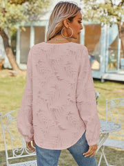 Blush pink textured puff sleeve v-neck blouse with all-over raised pattern.