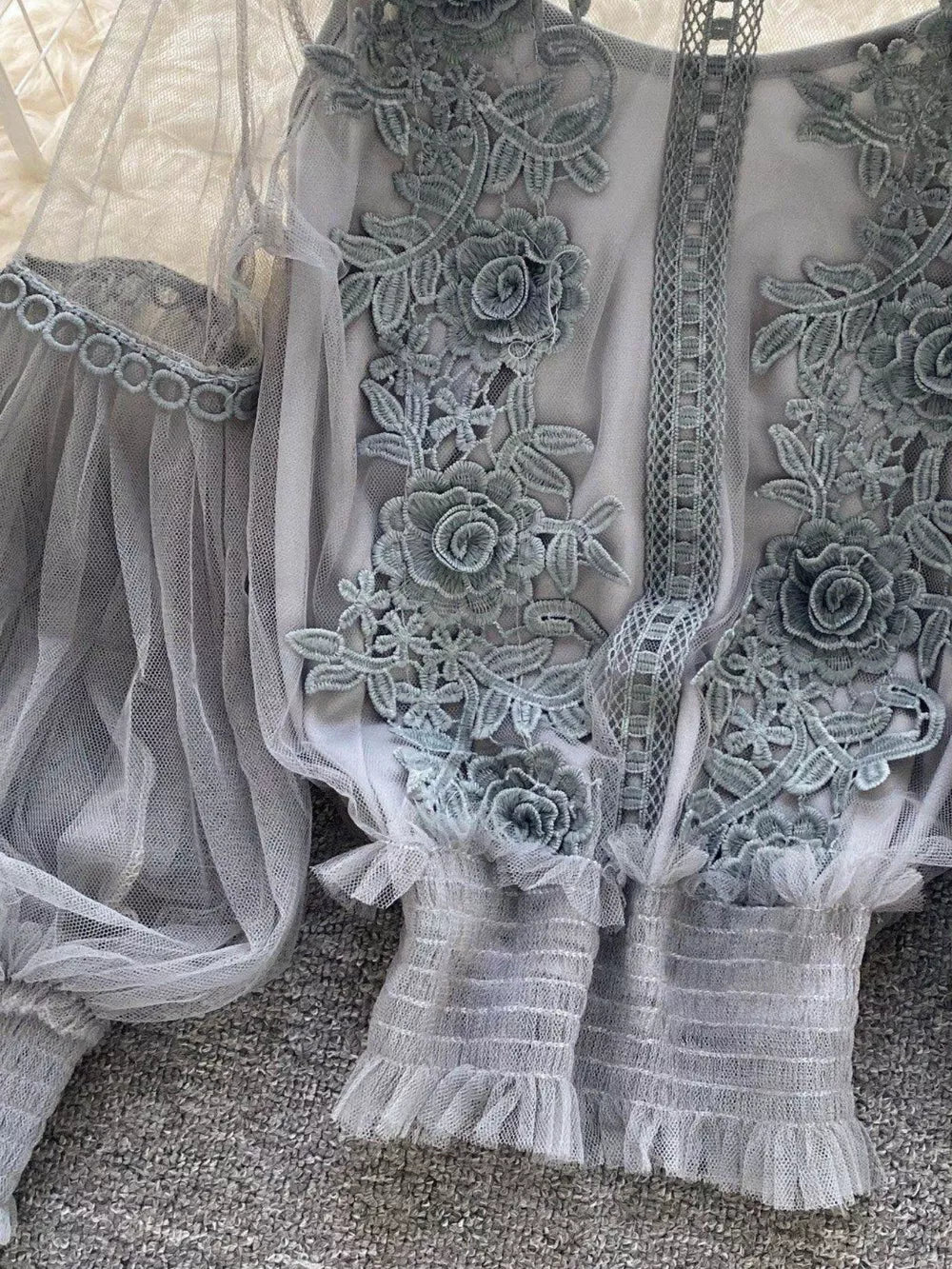 Gray lace embroidered blouse with sheer sleeves and ruffled cuffs.