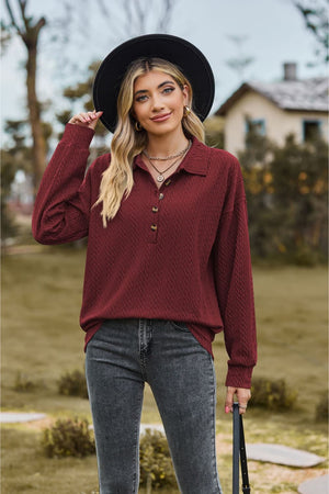 Burgundy textured knit polo shirt with buttoned neckline and long sleeves.