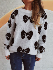 White knit sweater with black bow pattern, crew neck, relaxed fit