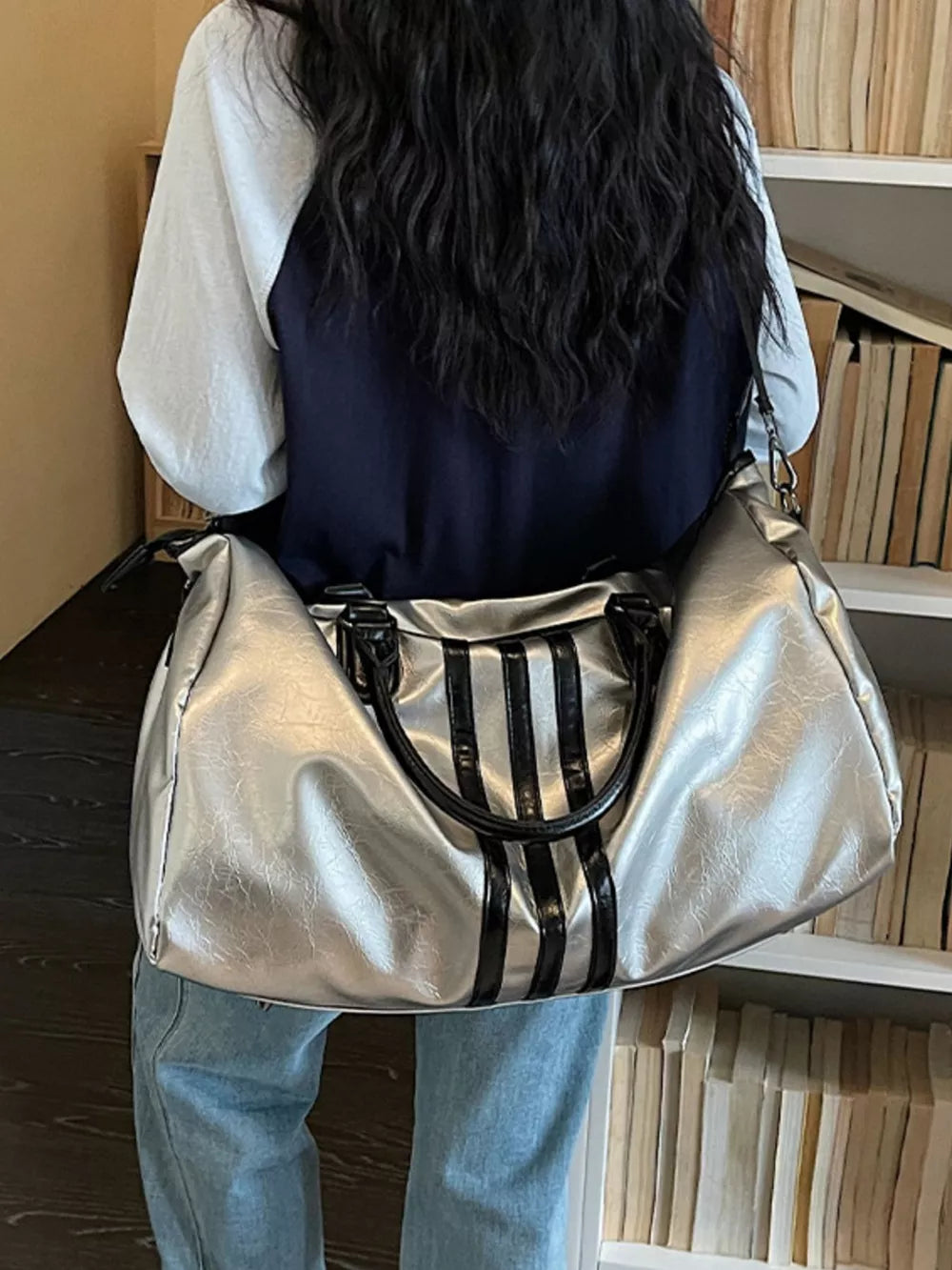 Sleek silver metallic duffle bag with black stripes and handles.