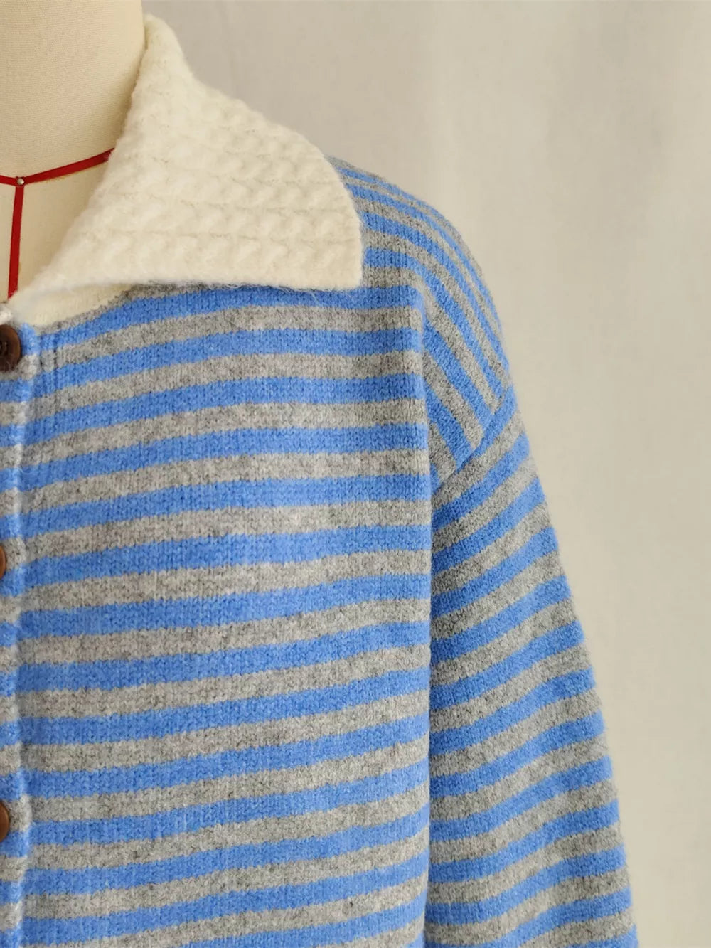 Blue and gray striped knit cardigan with textured white collar and button front.