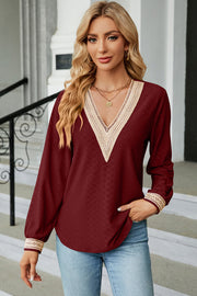 Burgundy textured V-neck blouse with lace trim on neckline and cuffs.