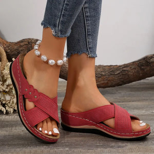 Red perforated cross-strap comfort sandals with white stitching and decorative studs.