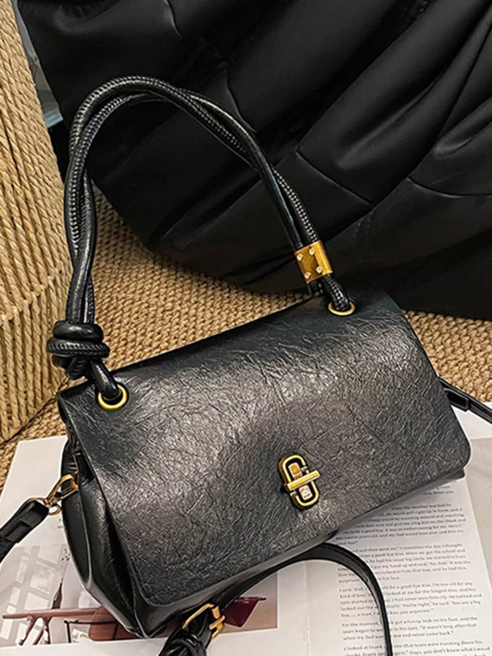 Black leather crossbody bag with twisted handle and gold clasp closure