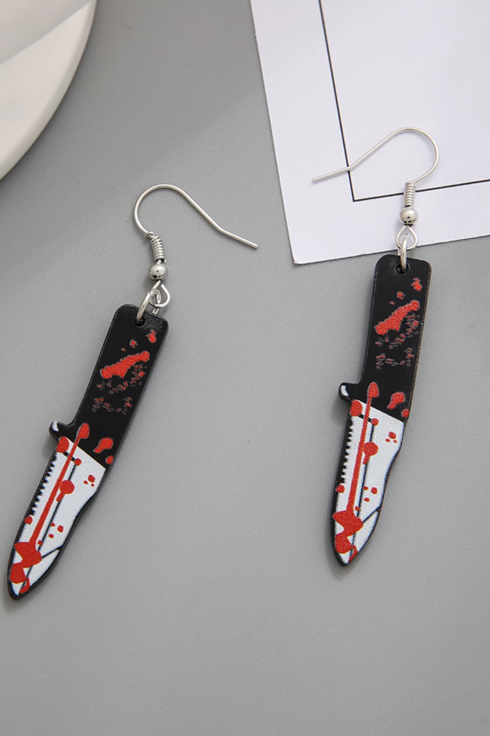 Gory blade drop earrings with red splatter detail.