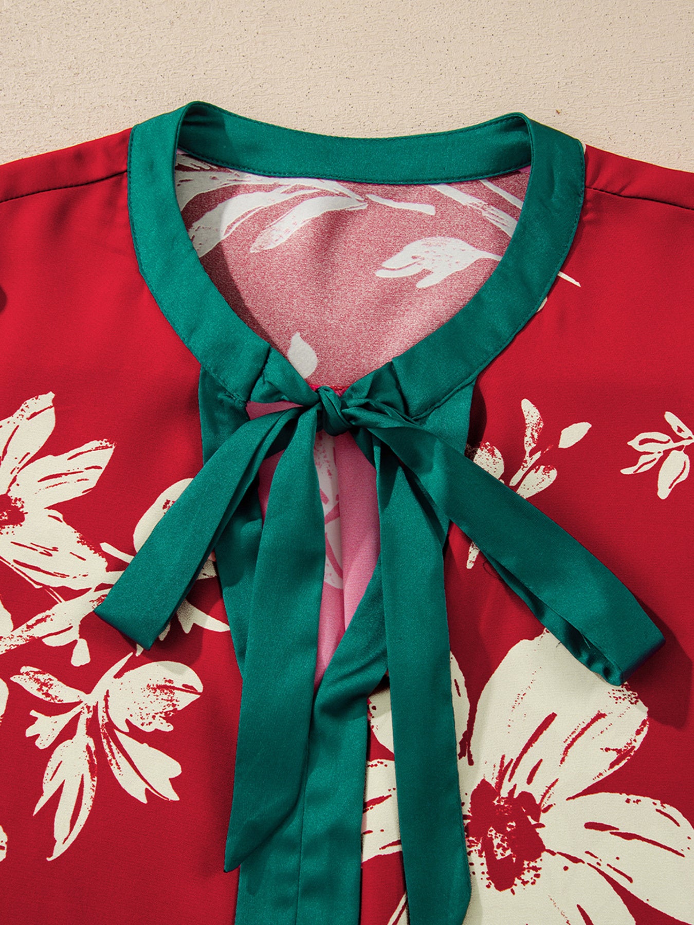 Red floral print blouse with green trim and a tied bow detail at the neckline.