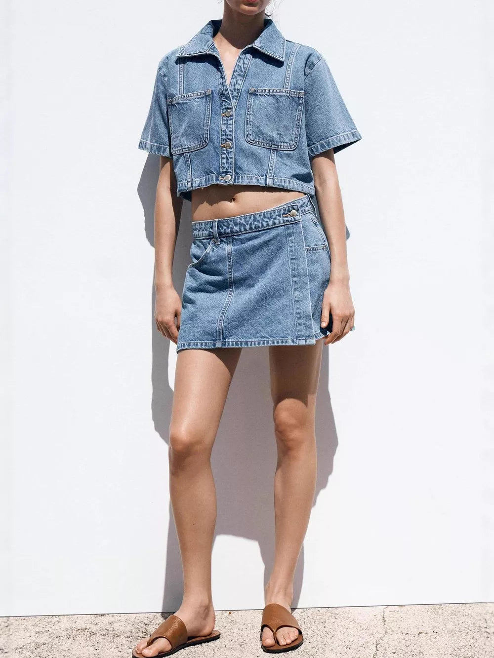 Denim cropped button-up top and skort set with contrast stitching.