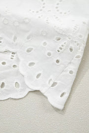 White cotton mini dress with eyelet embroidery and scalloped hem detail.