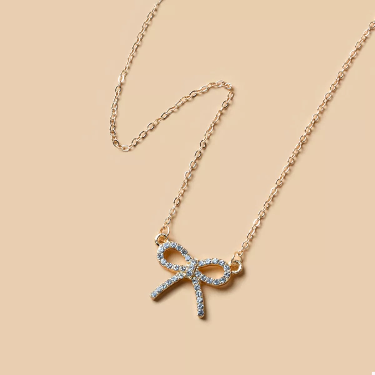Gold bowknot pendant necklace with clear crystals on a delicate chain