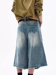 Men's distressed wide-leg denim shorts in light blue with frayed hem.