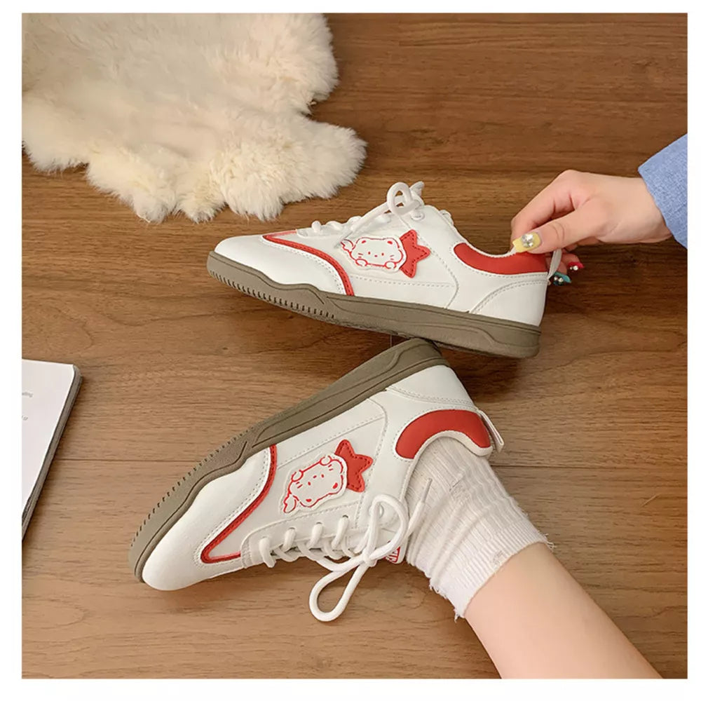 White and red lace-up sneakers with cartoon character accents and playful details.