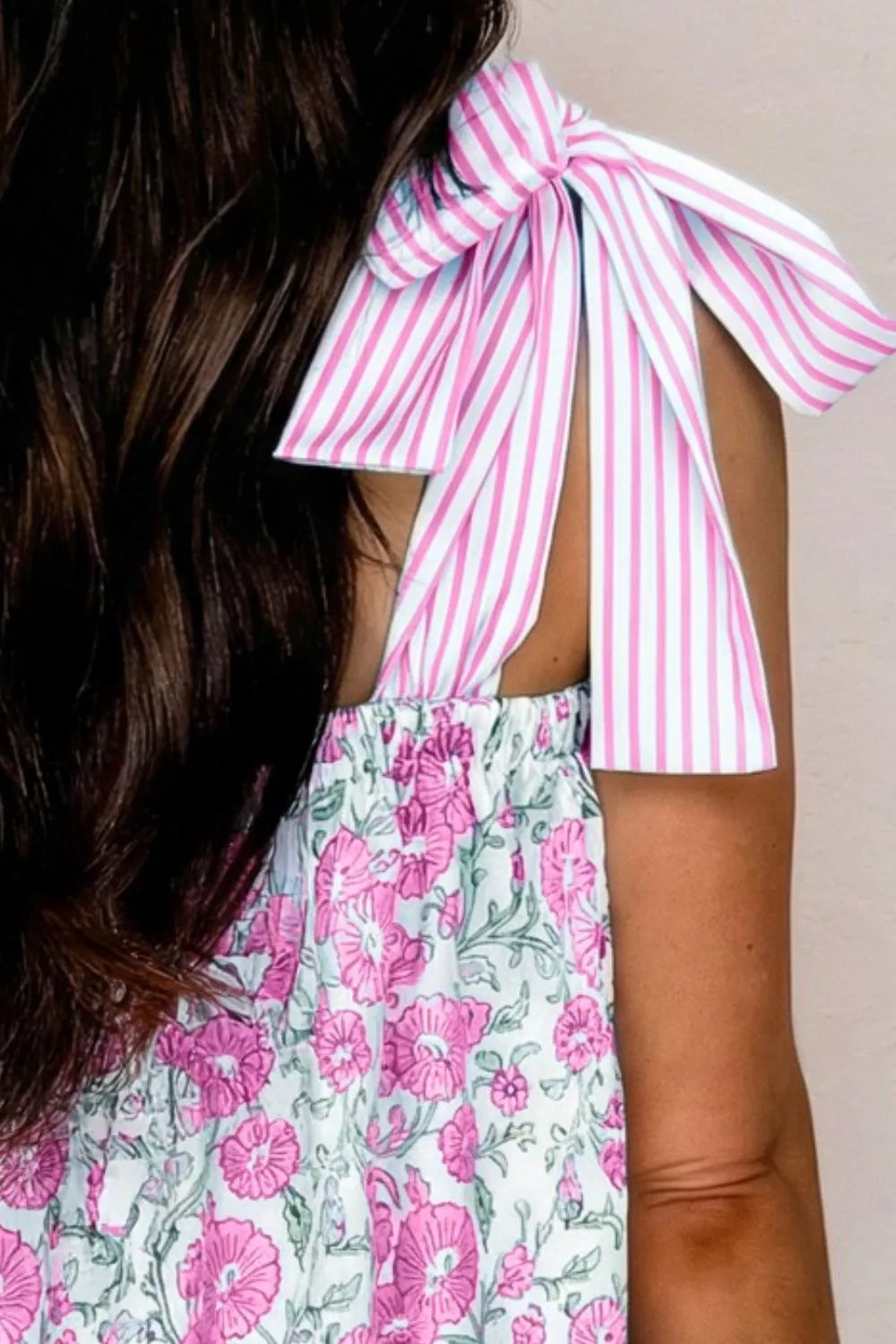 Floral mini dress with pink and white striped tie shoulders and a pink floral print skirt.