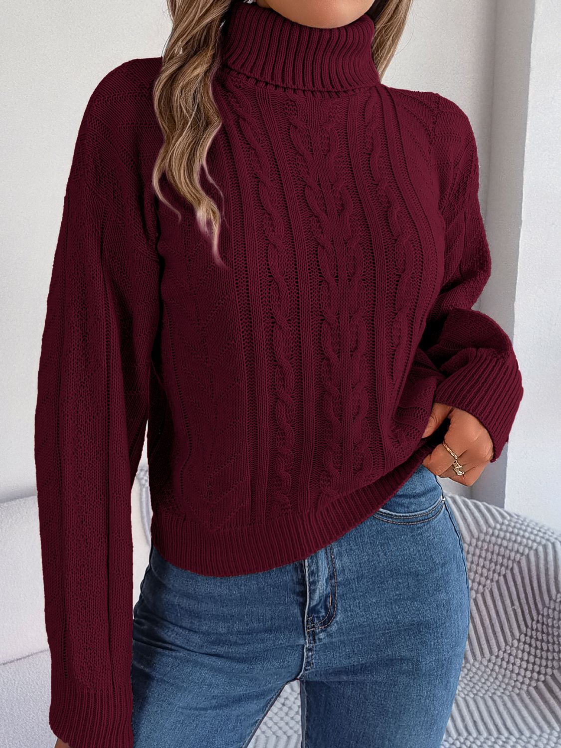 Burgundy cable knit turtleneck sweater with drop shoulder and ribbed cuffs.