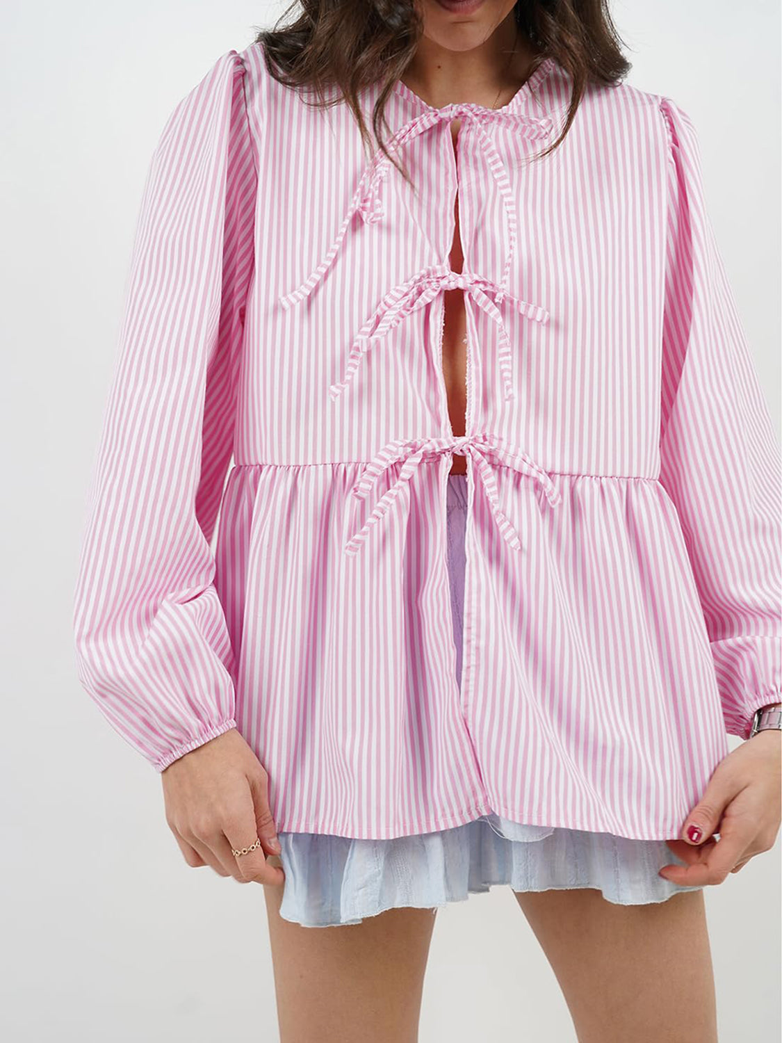 Pink and white striped peplum blouse with voluminous sleeves and tie-front closure.